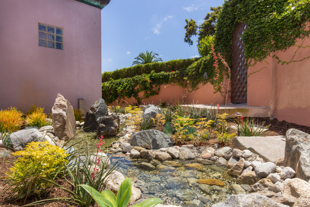 Design ideas for a mid-sized coastal partial sun courtyard river rock landscaping in San Diego for summer.