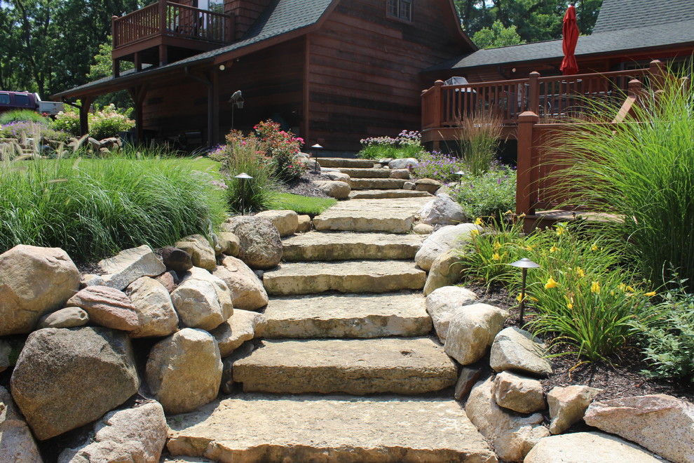 This is an example of a rustic sloped formal full sun garden in Chicago with a garden path and natural stone paving.