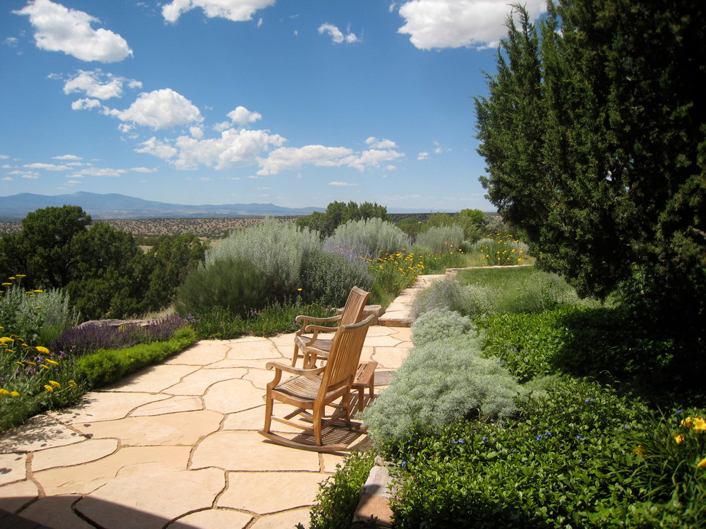 Mittelgroßer Mediterraner Garten hinter dem Haus, im Sommer mit direkter Sonneneinstrahlung und Natursteinplatten in Albuquerque