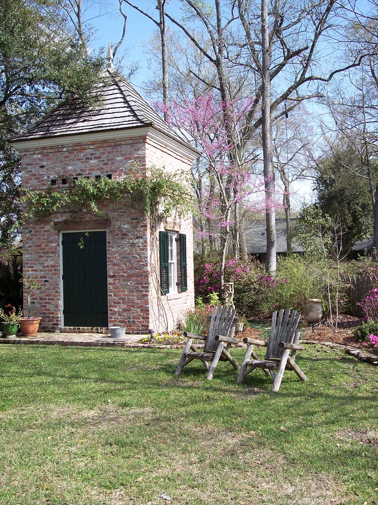Exempel på en mellanstor klassisk formell trädgård i delvis sol längs med huset på sommaren, med marksten i tegel