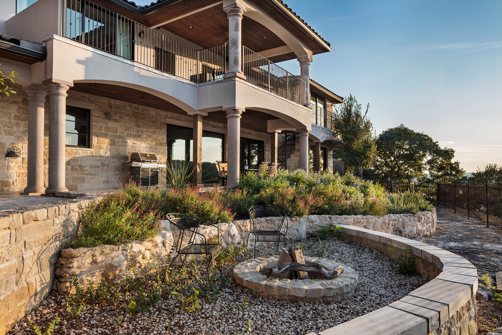 Design ideas for a large traditional sloped xeriscape full sun garden for summer in Austin with a fire feature and natural stone paving.