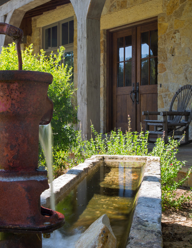 Foto di un grande giardino rustico esposto in pieno sole davanti casa con fontane e ghiaia