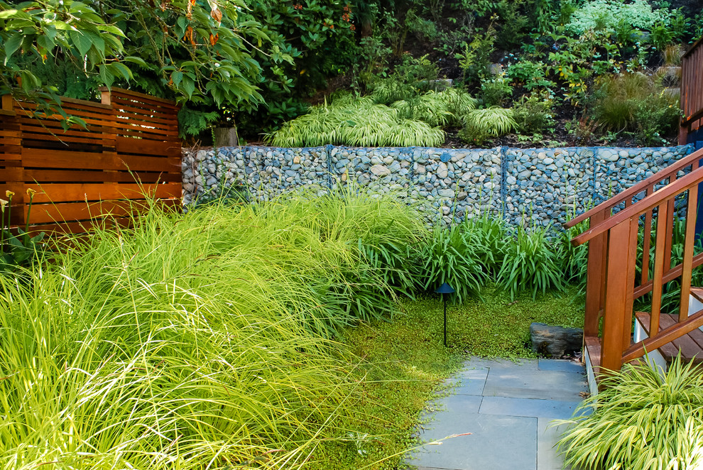This is an example of a small drought-tolerant and partial sun front yard stone retaining wall landscape in Seattle.