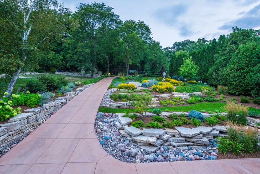 Photo of a large traditional front driveway full sun garden in Milwaukee with a retaining wall and gravel.