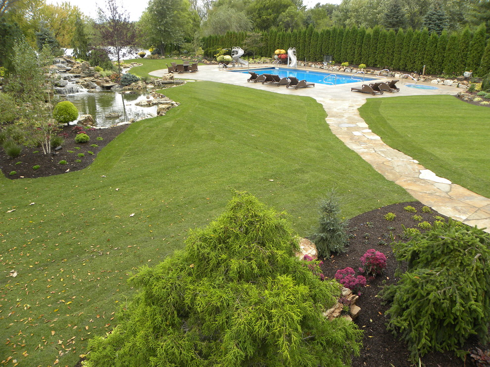 This is an example of a huge traditional partial sun backyard stone water fountain landscape in Chicago for summer.