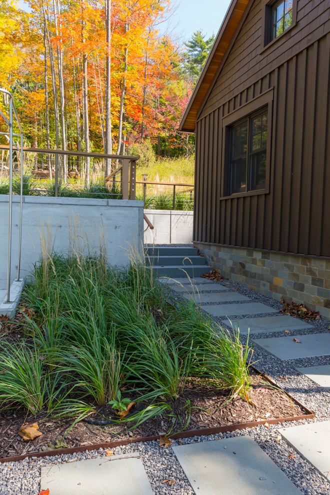 Esempio di un giardino xeriscape contemporaneo esposto a mezz'ombra di medie dimensioni e dietro casa in autunno con un muro di contenimento e pavimentazioni in pietra naturale