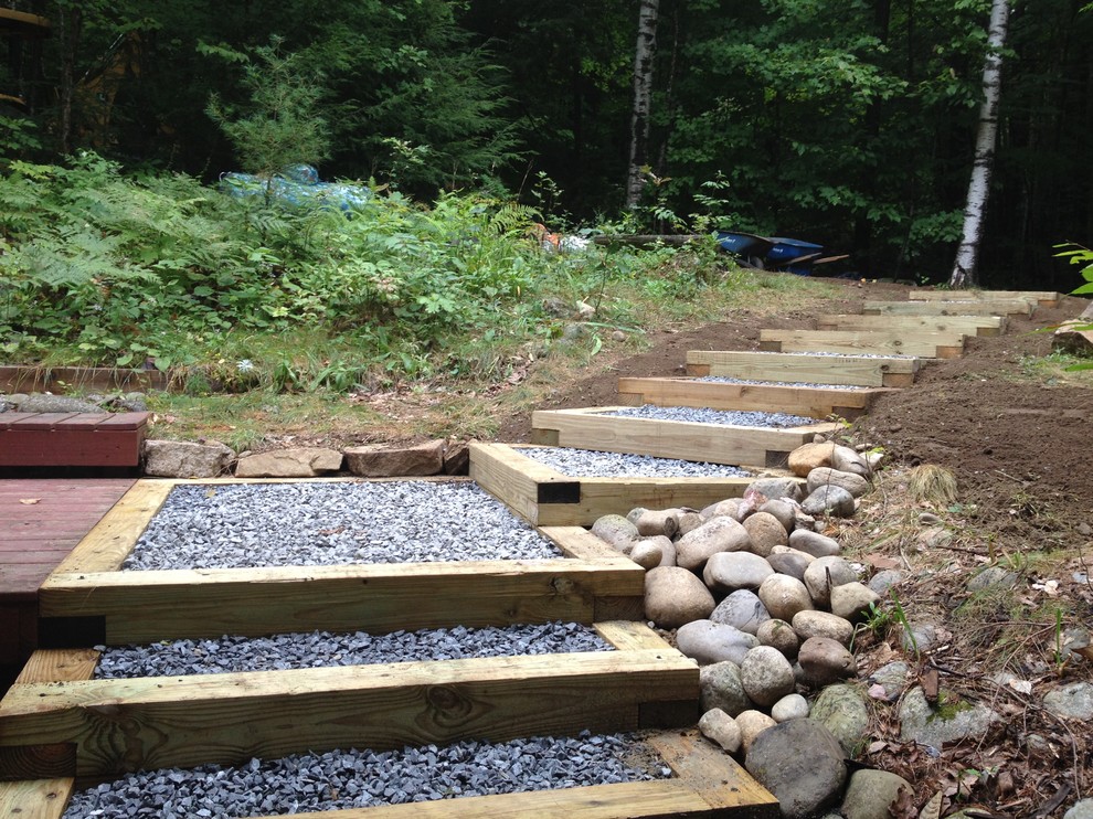 Small contemporary sloped fully shaded garden for summer in Portland Maine with a garden path and gravel.