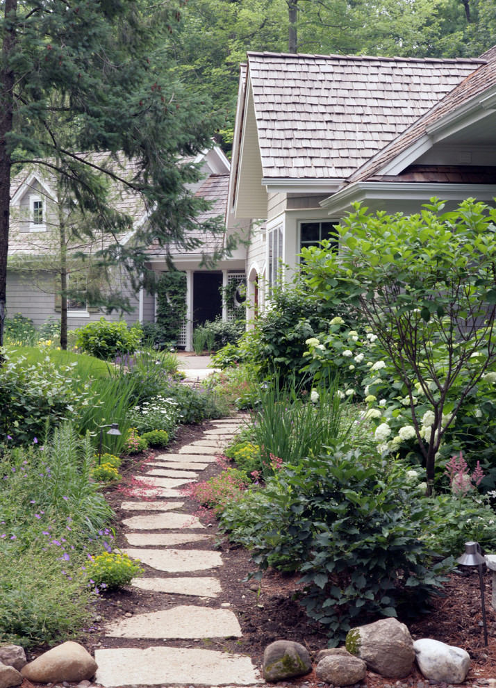 Bild på en stor vintage trädgård framför huset, med en trädgårdsgång och naturstensplattor