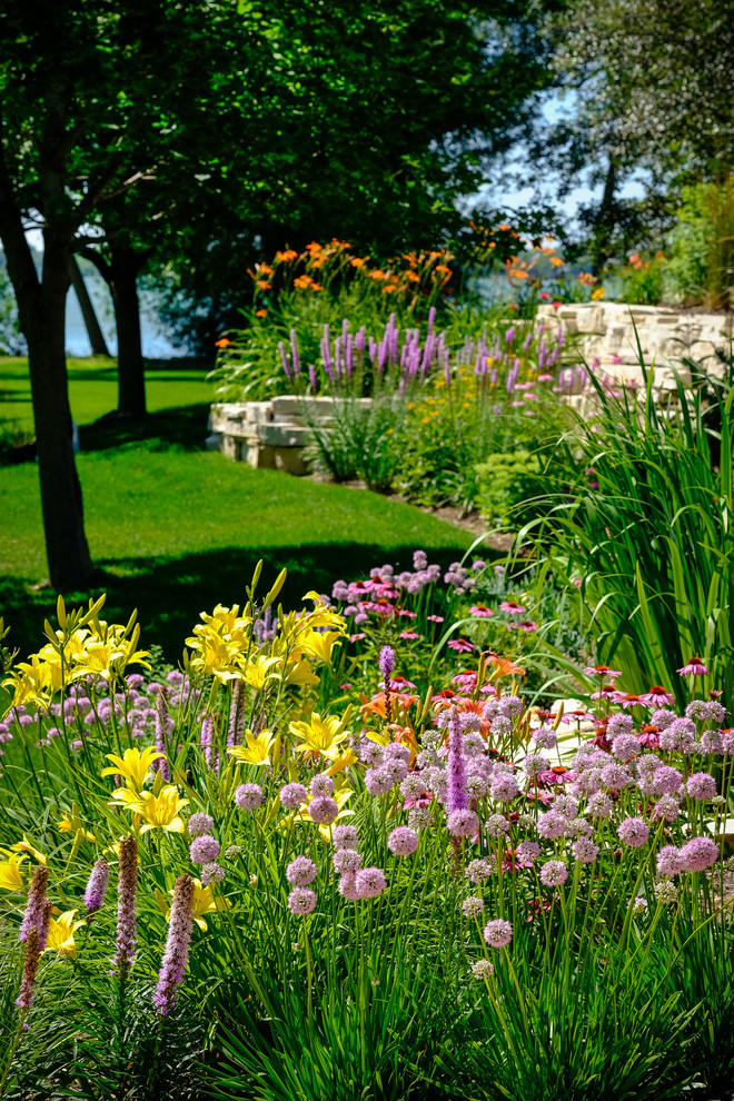 Immagine di un grande giardino xeriscape classico esposto in pieno sole davanti casa in estate con pavimentazioni in pietra naturale e un muro di contenimento