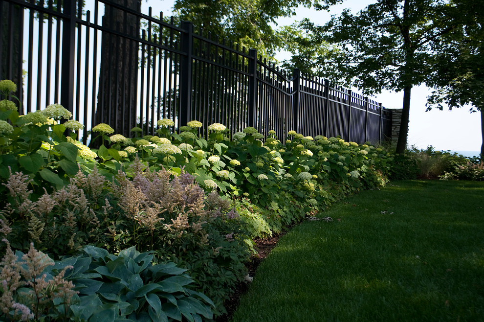 На фото: летний, солнечный регулярный сад на переднем дворе в классическом стиле с хорошей освещенностью с