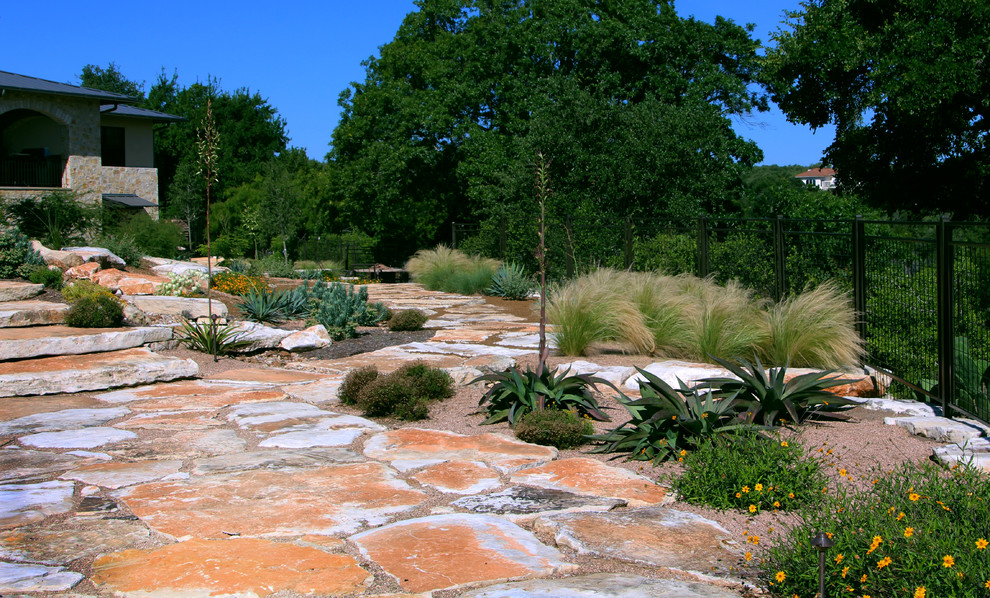 Imagen de jardín de secano mediterráneo grande en verano en patio trasero con exposición total al sol y adoquines de piedra natural