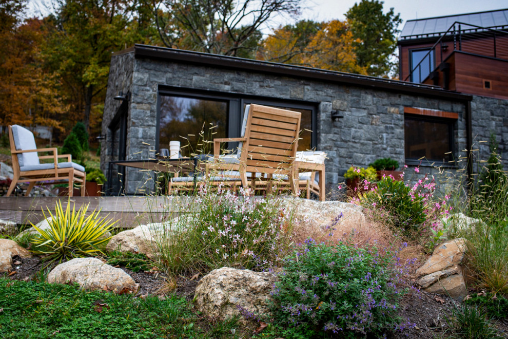 Пример оригинального дизайна: большой солнечный засухоустойчивый сад на боковом дворе в современном стиле с камнем в ландшафтном дизайне, хорошей освещенностью, настилом и с деревянным забором