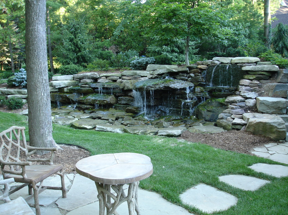 Großer, Halbschattiger Klassischer Vorgarten im Sommer mit Wasserspiel und Natursteinplatten in Grand Rapids