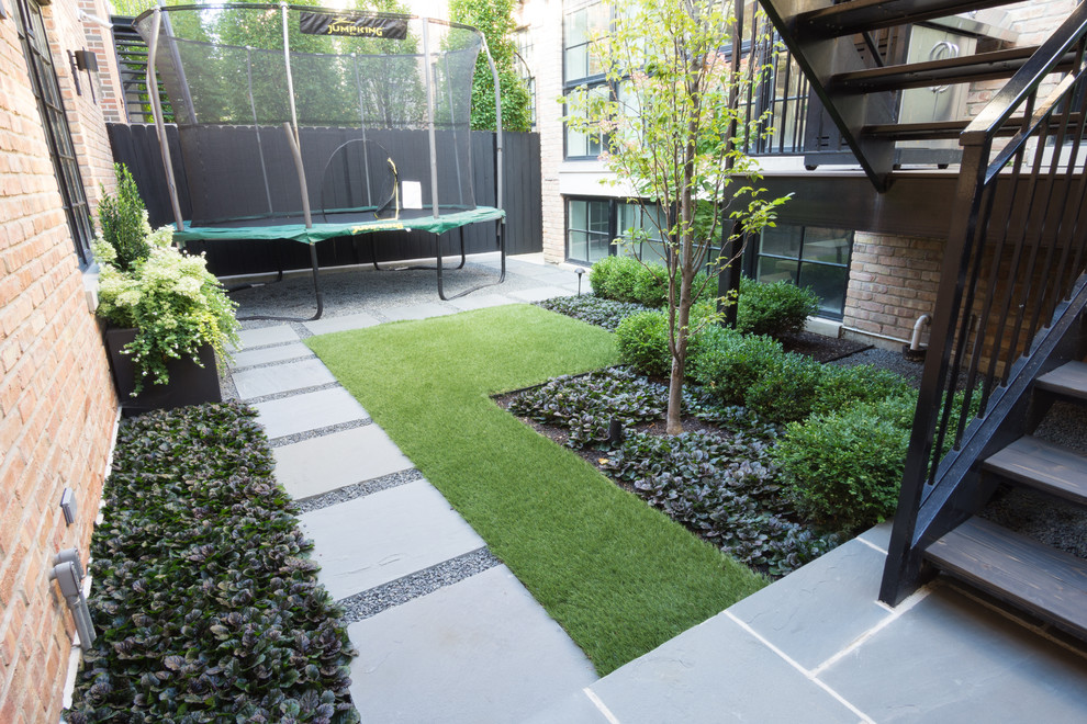 Diseño de jardín actual de tamaño medio en patio trasero con exposición parcial al sol y adoquines de piedra natural