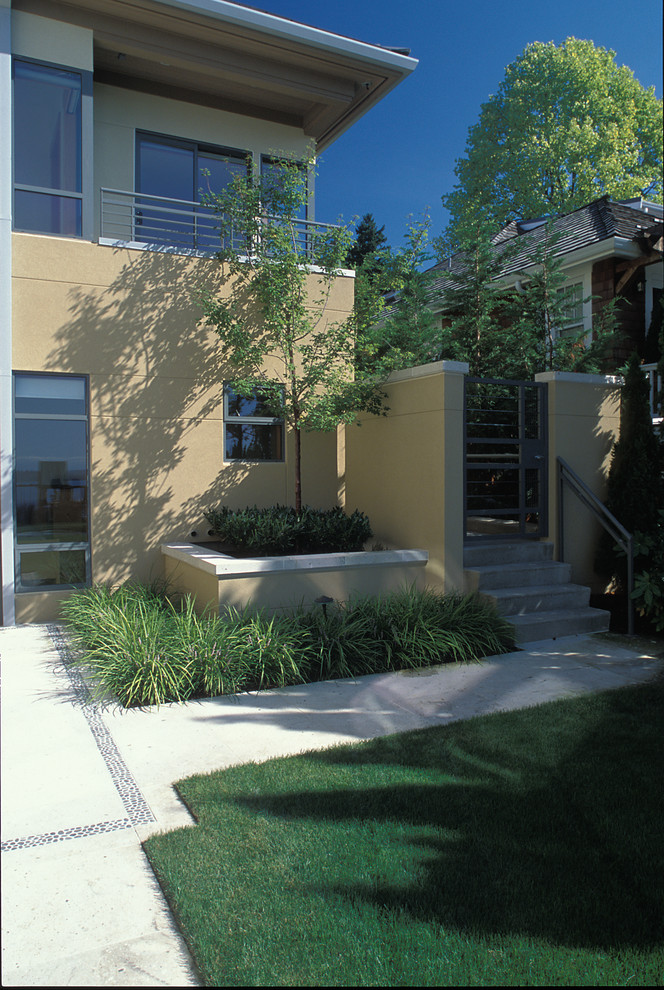 Exempel på en modern trädgård i delvis sol längs med huset