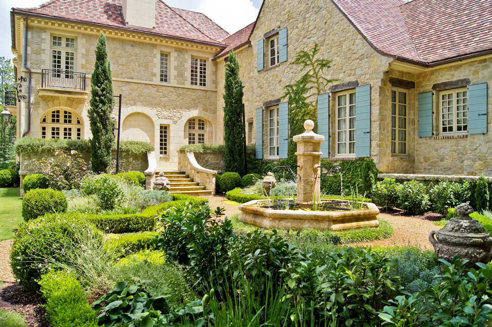 Ejemplo de jardín clásico en patio trasero con jardín francés y gravilla