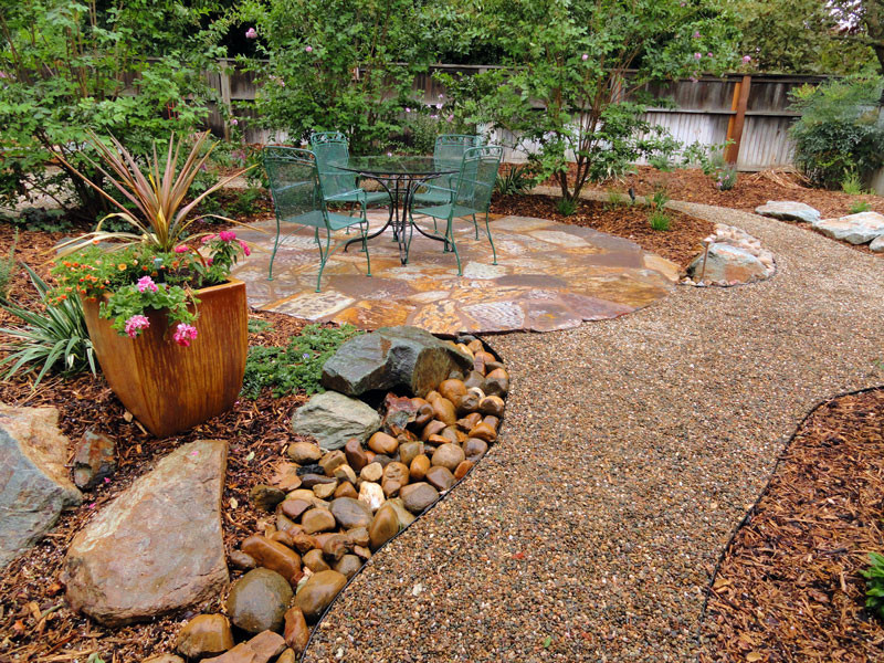 Halbschattiger Garten hinter dem Haus mit Sportplatz und Natursteinplatten in Sacramento