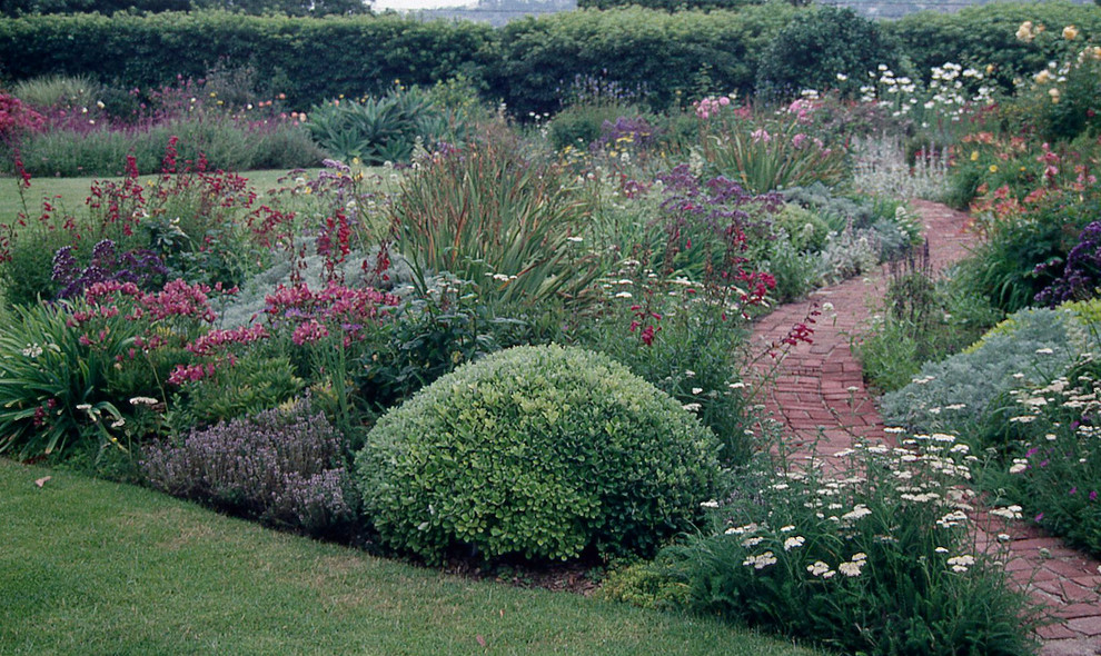 Foto på en stor amerikansk trädgård i full sol på sommaren, med marksten i tegel och en trädgårdsgång
