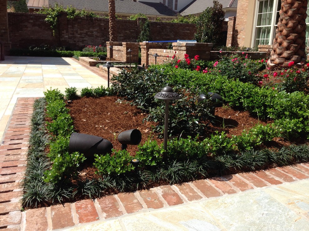Design ideas for a large traditional front partial sun garden in New Orleans with brick paving.