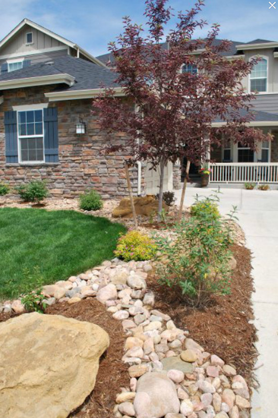 This is an example of a large classic front partial sun garden in Denver with a potted garden and brick paving.