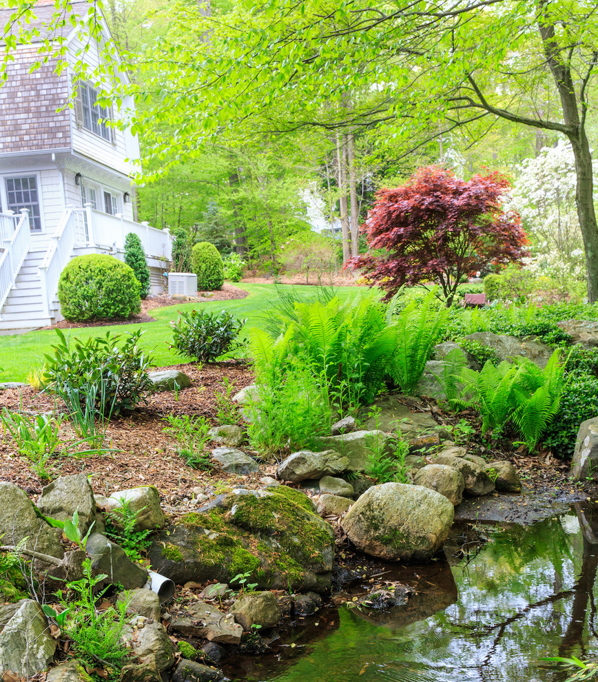 Exemple d'un jardin arrière chic de taille moyenne et au printemps avec un bassin, une exposition ensoleillée et du gravier.