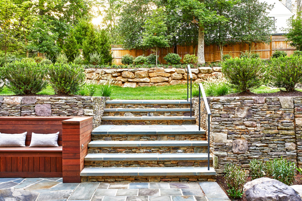 Foto di un grande giardino minimal esposto in pieno sole dietro casa in estate con un muro di contenimento e pavimentazioni in pietra naturale