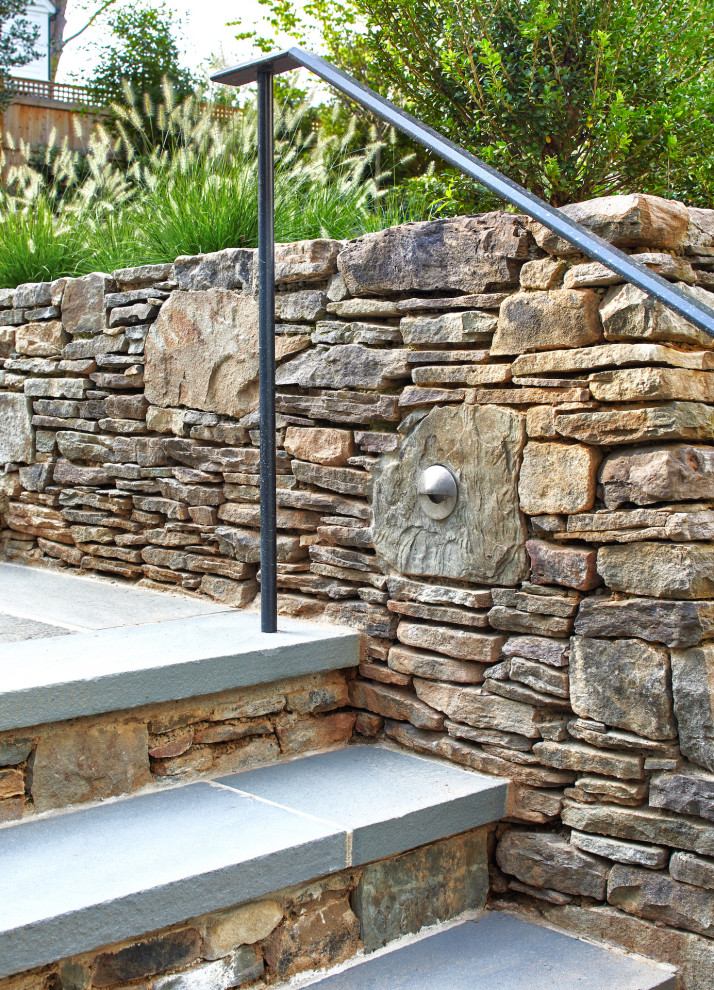 Foto di un giardino design esposto in pieno sole dietro casa con un muro di contenimento e pavimentazioni in pietra naturale