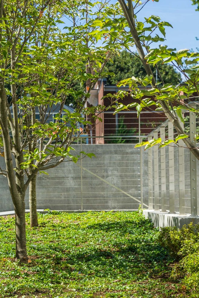 Modelo de jardín minimalista de tamaño medio en verano en patio lateral con jardín francés, muro de contención, exposición parcial al sol y adoquines de piedra natural