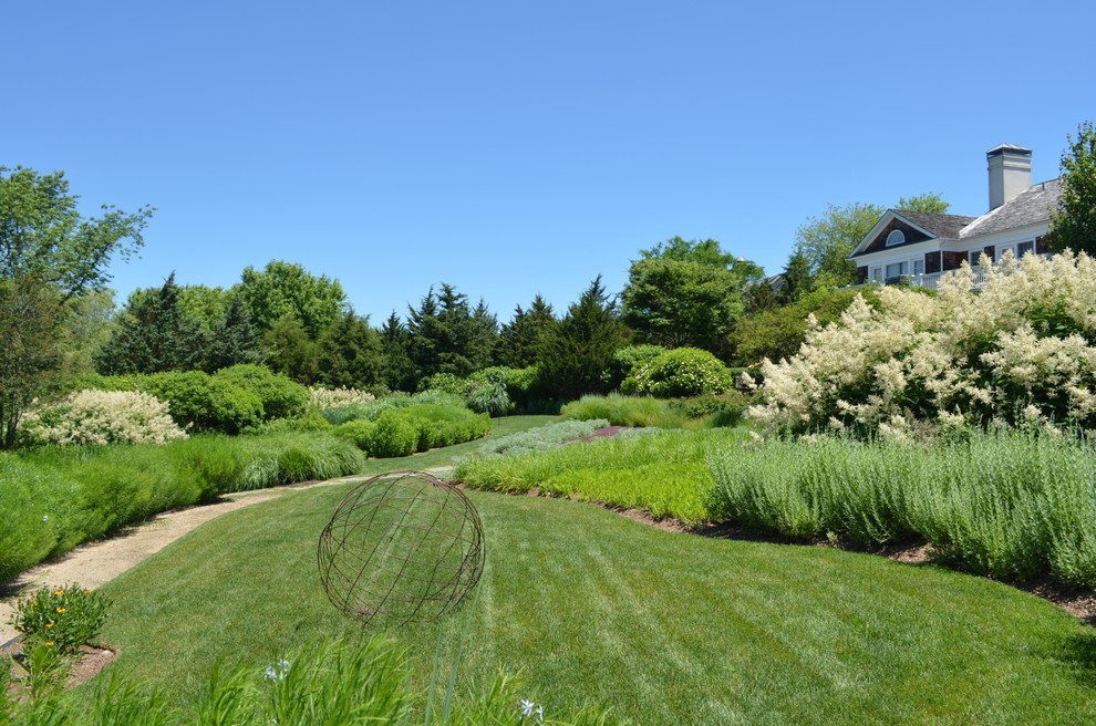 Photo of a large beach style sloped full sun garden for summer in New York with a potted garden and mulch.