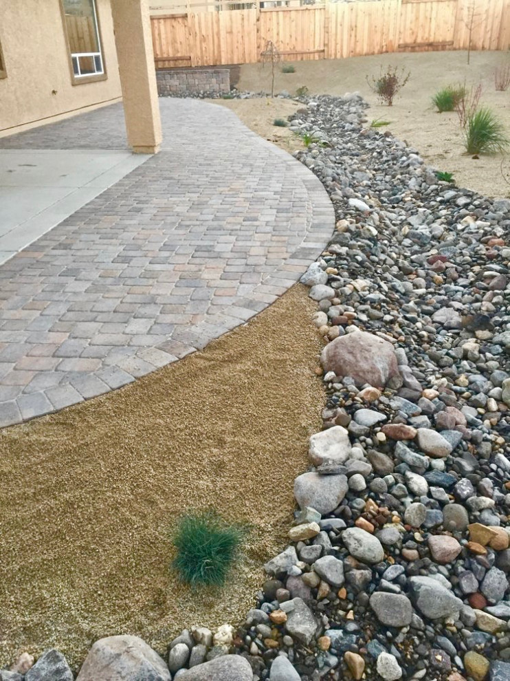Photo of a mid-sized traditional drought-tolerant, desert and full sun backyard stone landscaping in Las Vegas for summer.