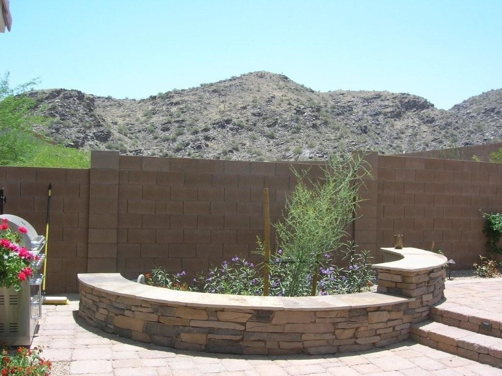 Exemple d'un jardin arrière sud-ouest américain de taille moyenne et l'été avec un mur de soutènement, une exposition ensoleillée et des pavés en béton.