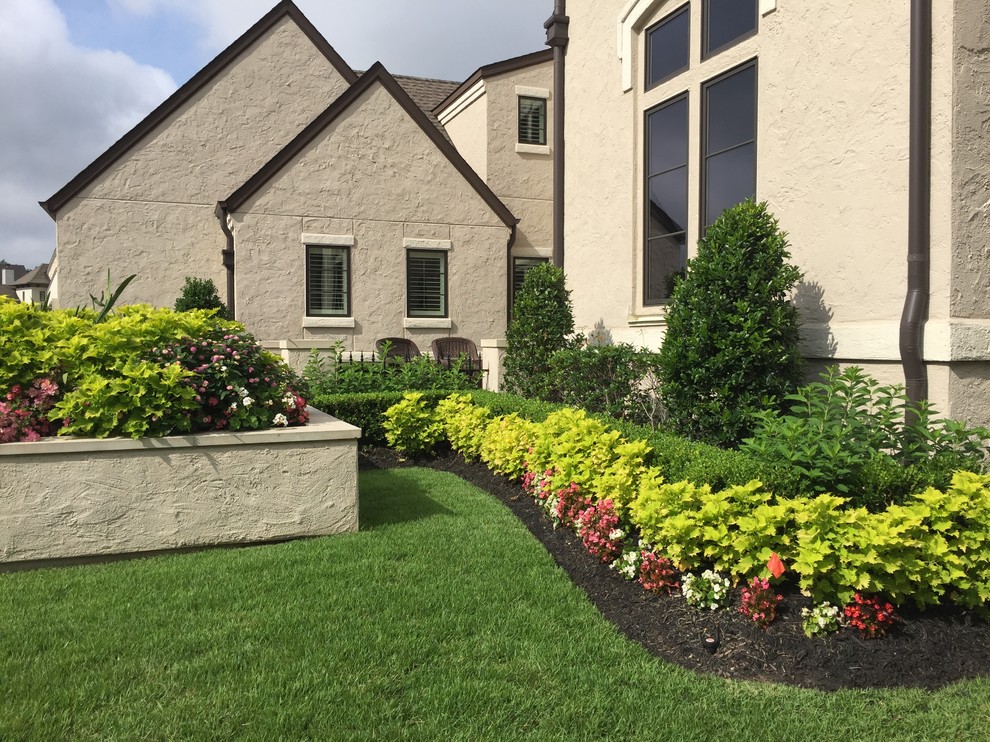 На фото: солнечный, весенний регулярный сад среднего размера на переднем дворе в классическом стиле с садовой дорожкой или калиткой, хорошей освещенностью и мульчированием