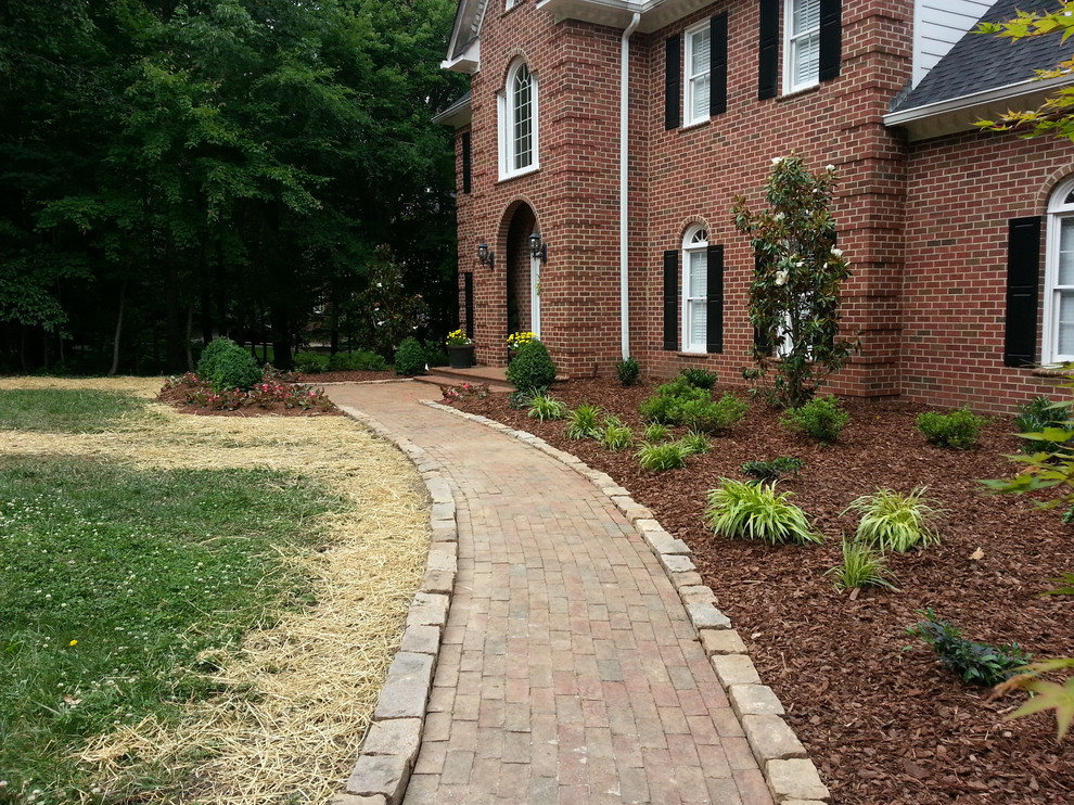 This is an example of a medium sized traditional front full sun garden in Raleigh with brick paving.
