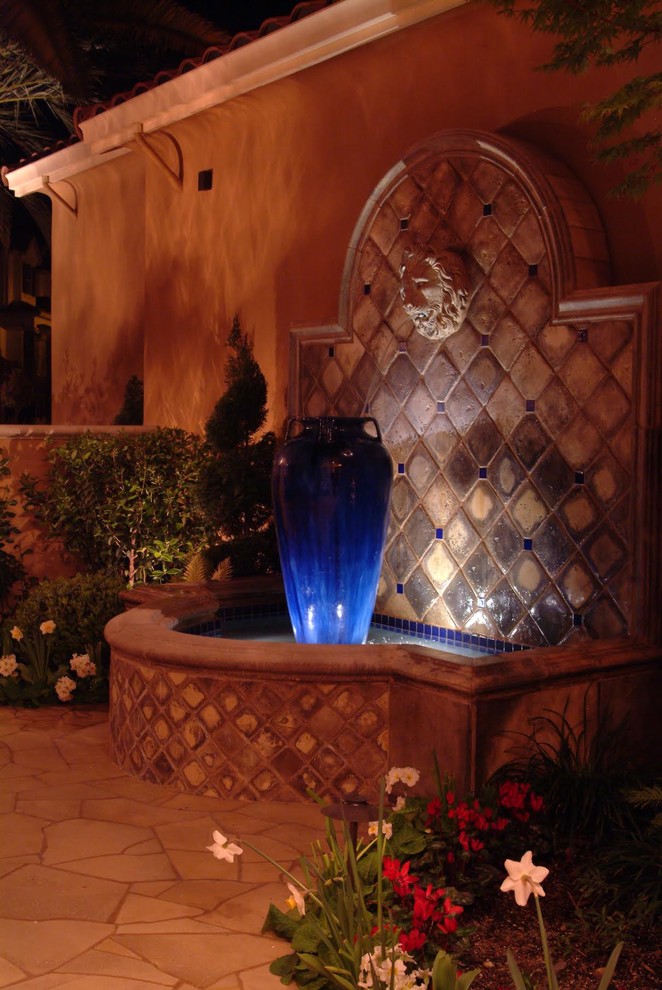 Imagen de jardín mediterráneo en patio con fuente y adoquines de hormigón