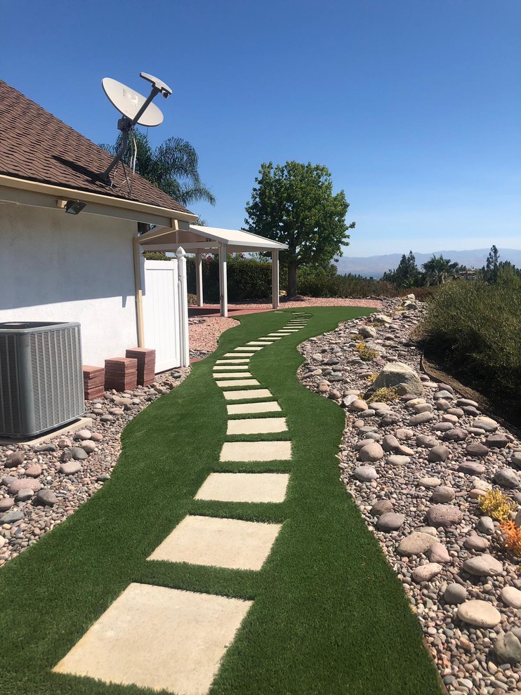This is an example of a medium sized modern back xeriscape full sun garden in Los Angeles with a garden path and natural stone paving.