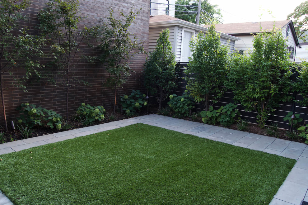 This is an example of a small modern full sun backyard concrete paver landscaping in Chicago.