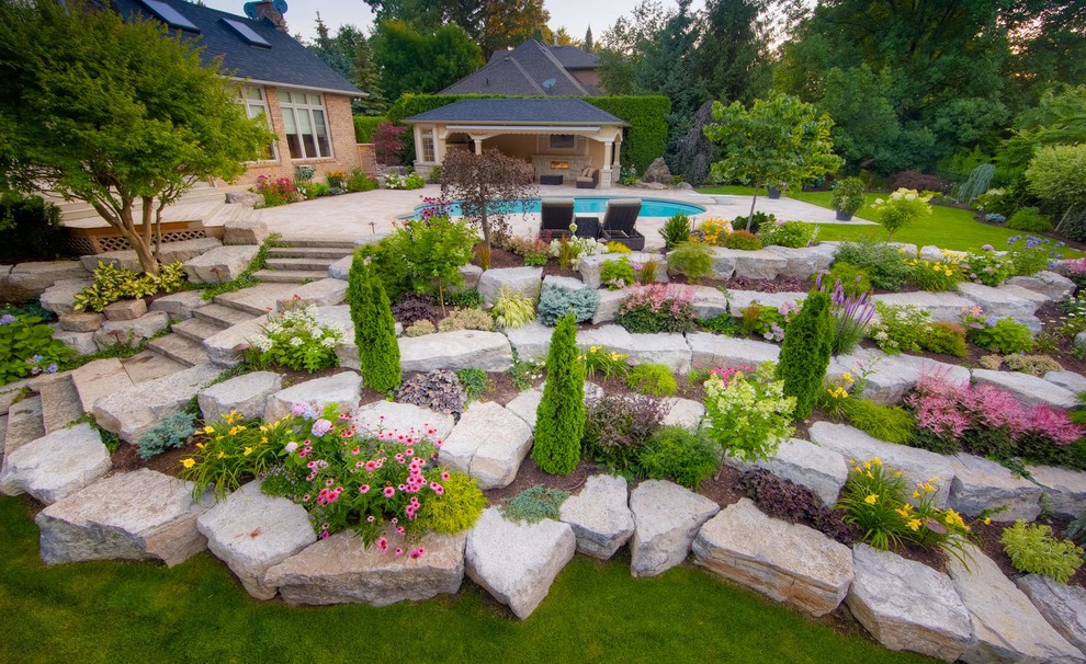 Idee per un ampio giardino chic esposto in pieno sole in estate con un pendio, una collina o una riva, pavimentazioni in pietra naturale e sassi e rocce