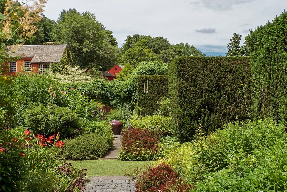 Cette image montre un jardin à la française arrière traditionnel avec des pavés en béton.