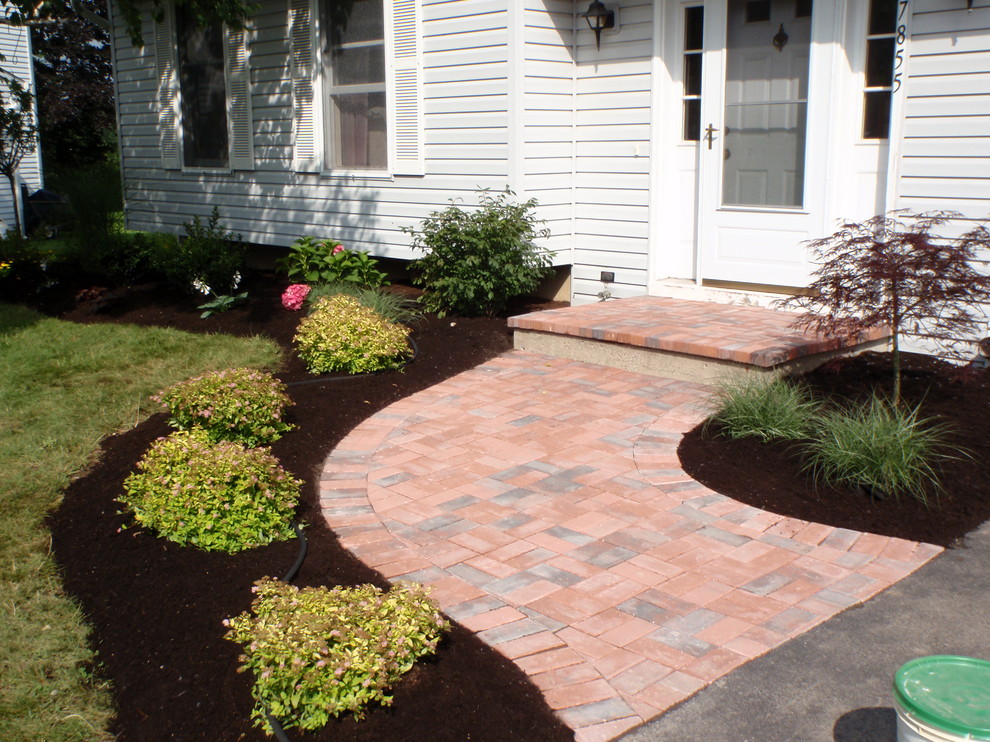 This is an example of a large classic front full sun garden for spring in New York with brick paving and a garden path.