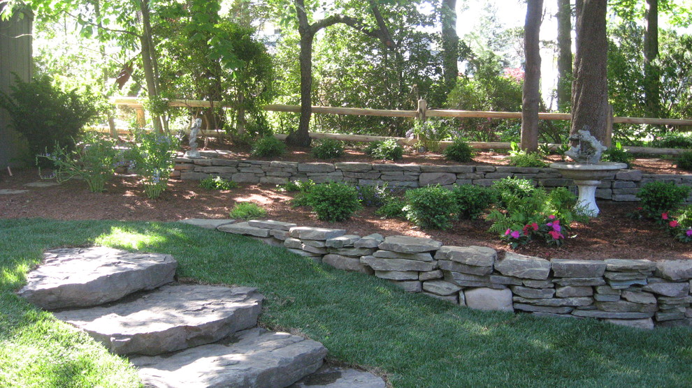 This is an example of a rustic sloped formal garden in New York with a retaining wall.