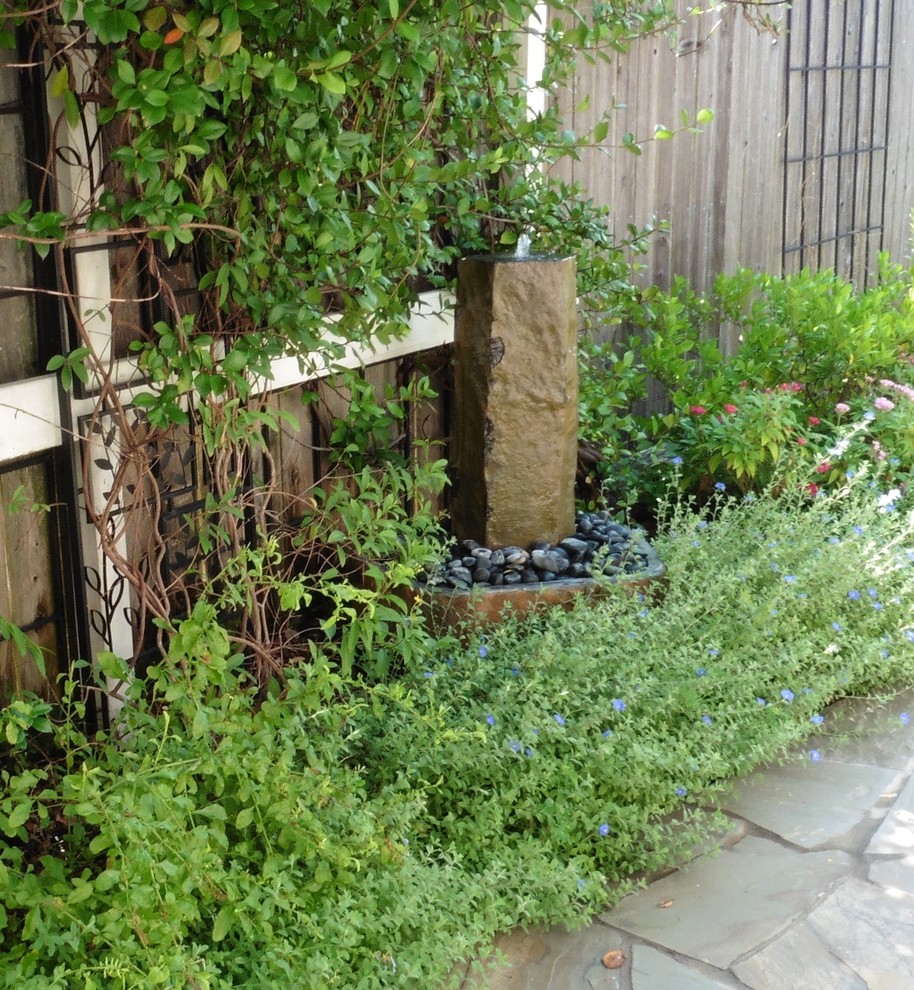 Foto de jardín moderno de tamaño medio en verano en patio trasero con jardín francés, fuente, exposición total al sol y adoquines de piedra natural
