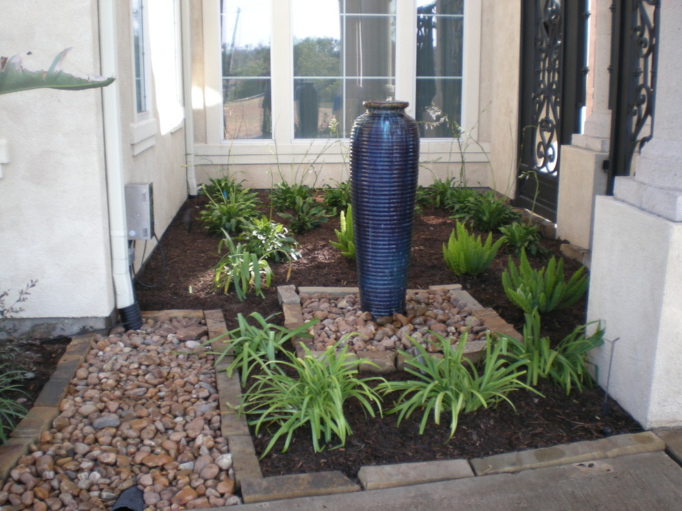 Inspiration for a medium sized front partial sun garden in Houston with a water feature and gravel.