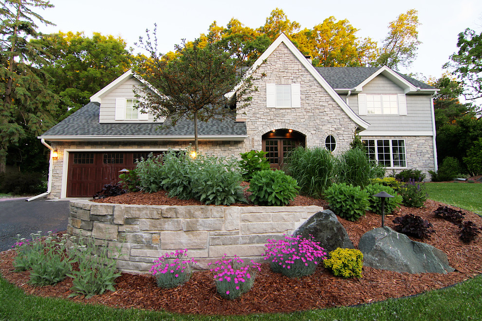 This is an example of a large traditional front full sun garden for spring in Minneapolis with a retaining wall and mulch.