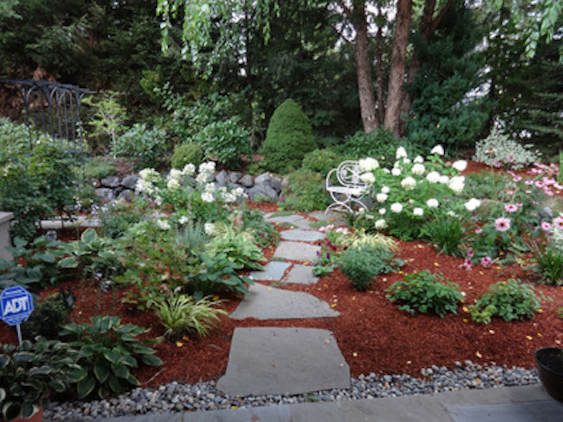Immagine di un piccolo giardino formale tradizionale esposto a mezz'ombra dietro casa in primavera con un ingresso o sentiero e pavimentazioni in pietra naturale