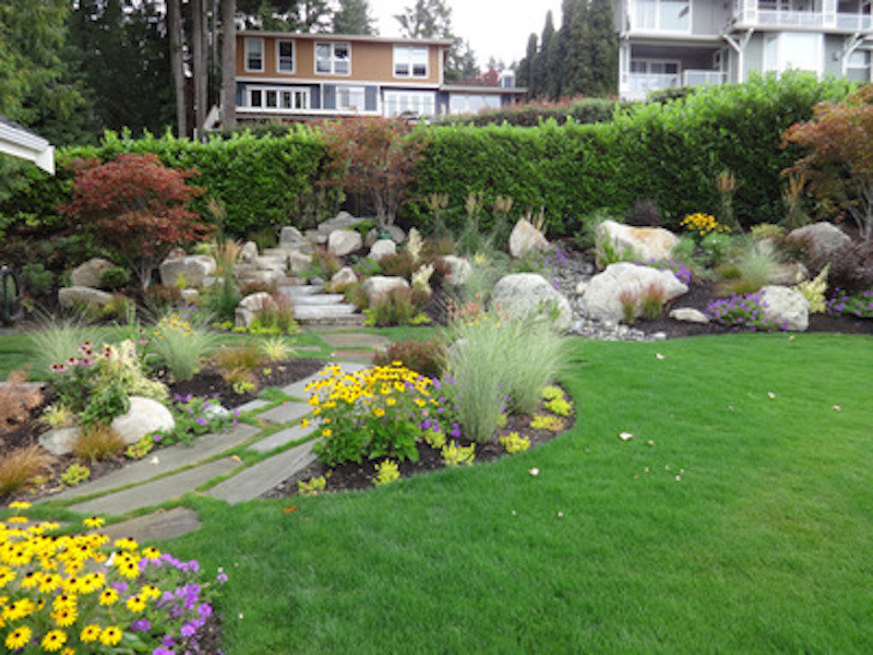 This is an example of a large classic back formal partial sun garden for summer in Seattle with a garden path and natural stone paving.