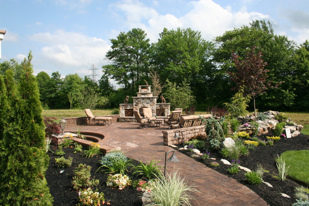 This is an example of an expansive traditional back full sun garden for summer in Philadelphia with a fire feature and concrete paving.