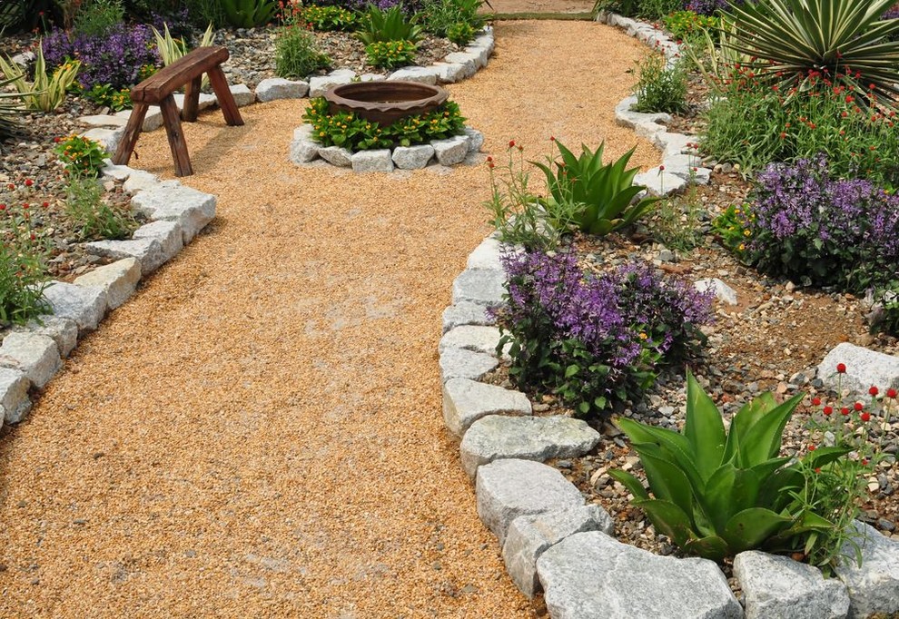 Exempel på en klassisk bakgård i full sol, med en trädgårdsgång och grus