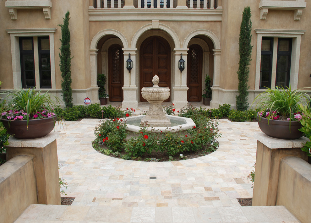 Ejemplo de jardín mediterráneo grande en patio trasero con fuente, exposición parcial al sol y adoquines de piedra natural