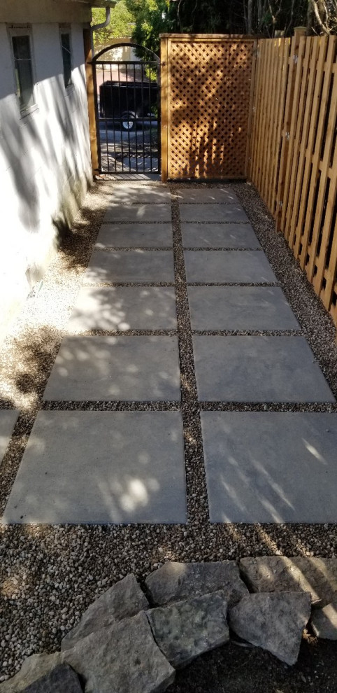 Photo of a medium sized contemporary back formal full sun garden in Montreal with a garden path, decorative stones and a wood fence.