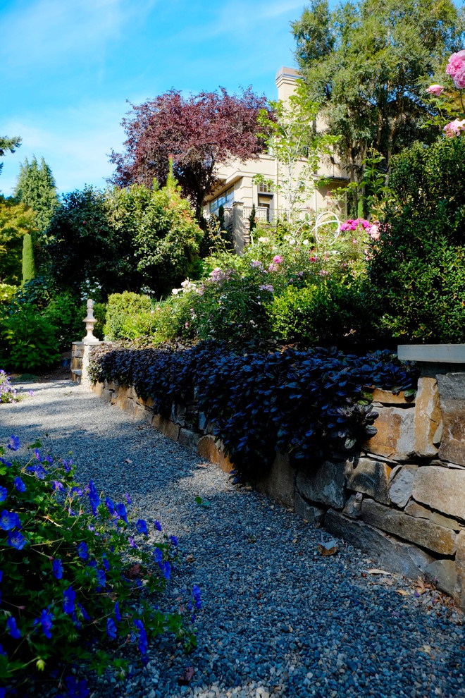 Design ideas for a mid-sized victorian full sun backyard gravel retaining wall landscape.